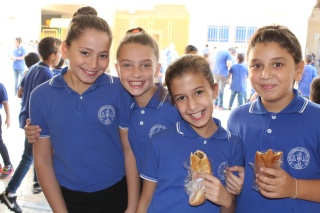 Four young children smiling for the camera and holding breadsticks 