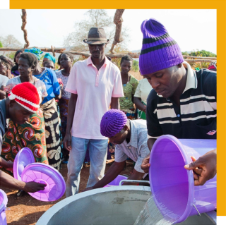 Volunteers fill a stove with water to prepare food