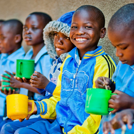 Children eating mugs of porridge