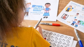Girl colouring in Marys Meals activity pack