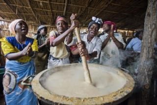 Volunteer cooks stirring large pot of porridge, Malawi