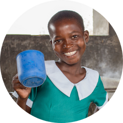 Susan, child from Malawi looking to camera smiling holding blue mug