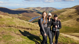 Three people in hiking gear on a hill taking part in the Artemis Pentland Peaks challenge