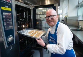 Gary Maclean with tray of biscuits going into oven