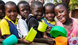 Children in Malawi queuing with mugs and bowls