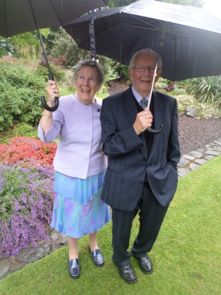 Mary's Meals supporter and husband stand under umbrellas in palace garden