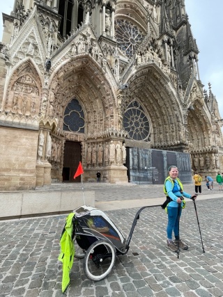 Woman in blue t-shirt towing trailer pictured in front of cathedral in France