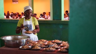 Volunteer wearing a Mary's Meals apron, plating up rice and beans