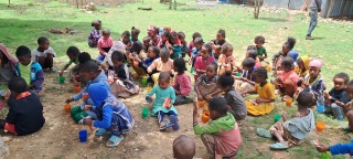 Children sitting in the ground in a crowd and eating in Tigray, Ethiopia