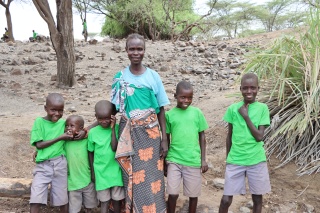 a woman, epeot, stands alongside five children in green t-shirts