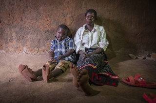 Son and mother sit beside each other in floor of home in rural Zambia