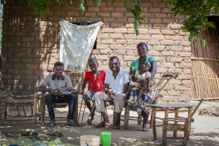 A family sit outside their house, Emmanuel Kunda and his wife Victoria Mbewe with their sons, Edgar, Benjamin and Evans Kunda (names changed)