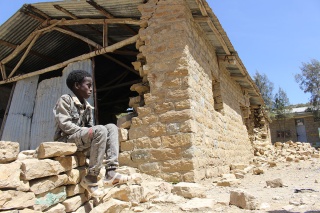 Child sitting outside a destroyed school