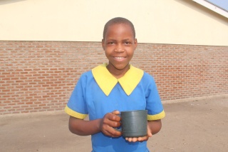 Dorophy, a school girl in Malawi, standing outside with a mug