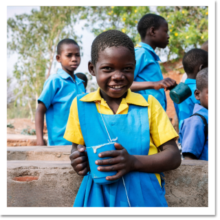 Child from Malawi holding a blue mug of porridge