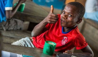 Work for us_Mary's Meals_Child with Food with Thumbs Up