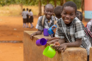 Children outside in Zambia with mugs of Mary's Meals porridge