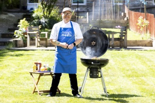 Gary Maclean stands next to a BBQ cooking
