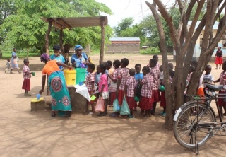 Women serve Mary's Meals to children lining up in Zambia