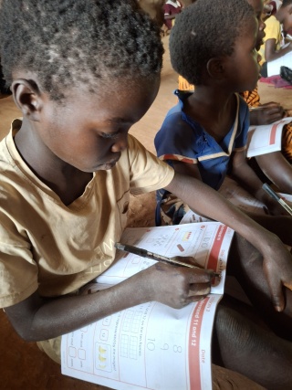 Lax and Dija write in their school workbooks
