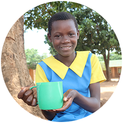 An image of a child named Ivy from Malawi, holding her mug of porridge