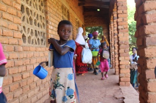 A child carries a mug outside school