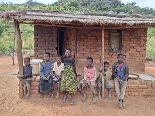 A family of seven sit outside a house in Malawi