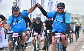 Image of two cyclists celebrating crossing the finish line