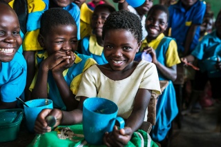 Image of a child in class happy with their school meal