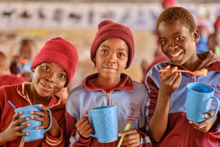 Children in Zimbabwe eating Mary's Meals porridge from mugs