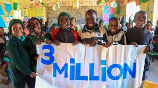 Image of children in class holding a 3 million sign