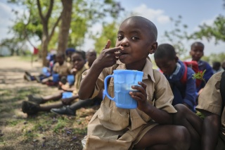 A child in Zimbabwe eating a mug of Mary's Meals porridge