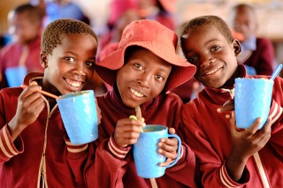 An image of three children in class enjoying their school meals