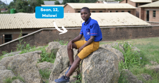 Sean in Malawi sitting on a rock