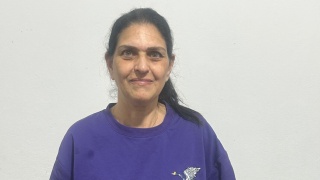 A cropped picture of a woman in a blue t-shirt stands inside