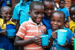 Children in Malawi with mugs of Mary's Meals porridge