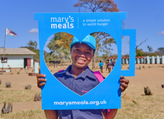 Child holding a Mary's Meals heart sign
