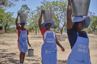Mary's Meals volunteers carrying buckets of water