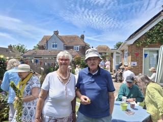 An older couple stand together at a garden party