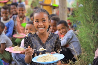 Girl eating a bowl of porridge in Ethiopia