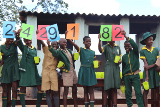 An image of children in Zimbabwe holding the number of children we feed
