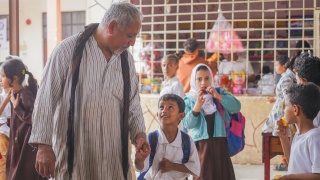 A man and his son hold hands outside