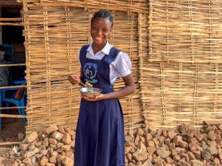 A girl smiling with a bowl of food