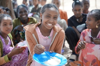 A girl eating and smiling with other girls