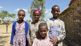 Three children and their mother stand outside smiling