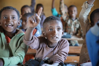 A boy with his hand up in class