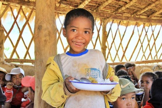 An image of a child in Madagascar holding their school meal. 