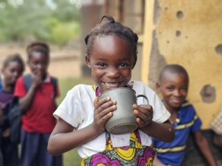 An image of a child smiling after enjoying her school meal