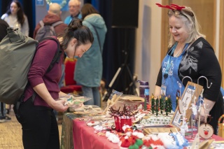 A shopper surveys various Charity Christmas gifts from Scottish makers as a Mary's Meals volunteer assists